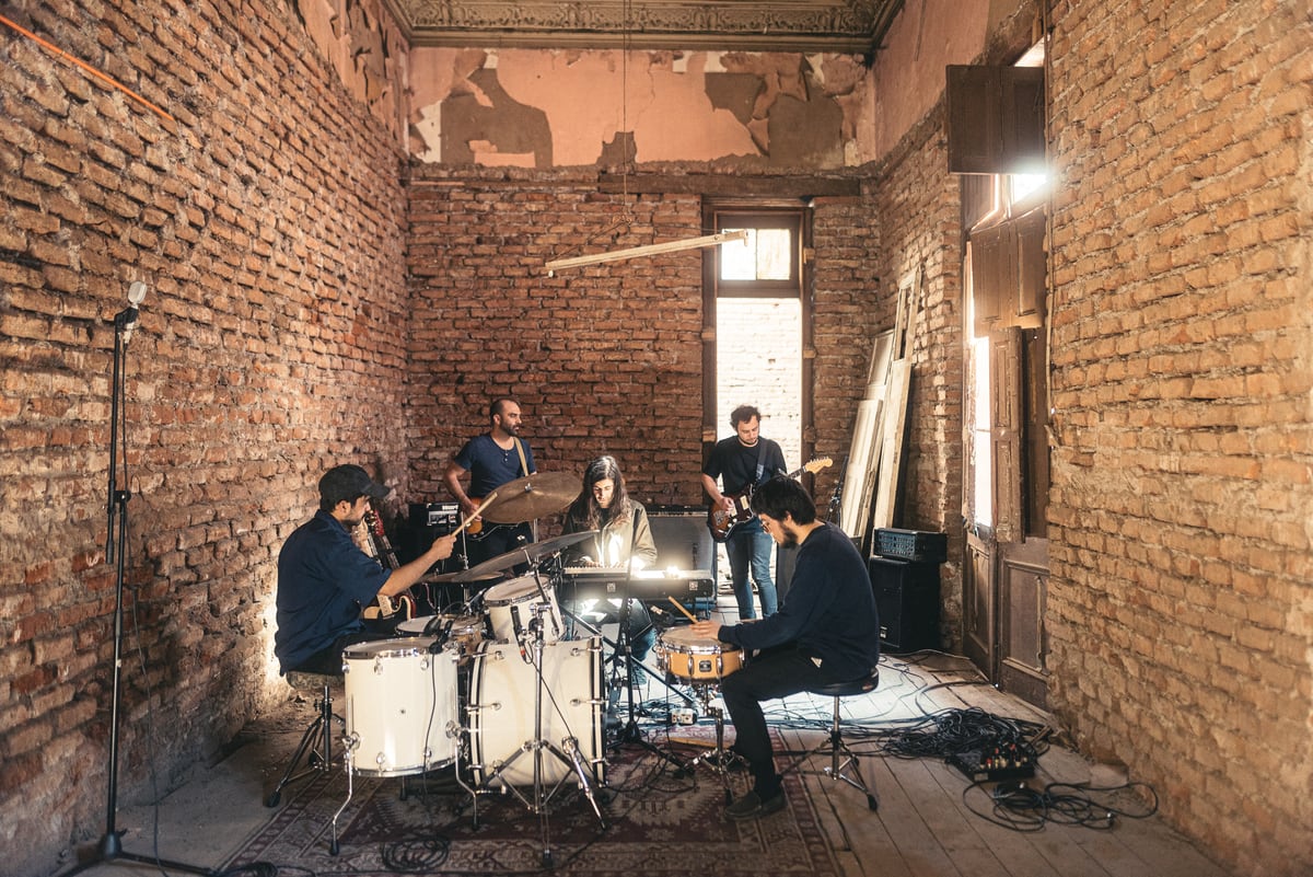 La Ciencia Simple tocando con guitarras, teclados y percusión en una sala de ladrillos